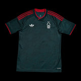 Kitted Up Nottingham Forest 2026/2027 kids away jersey in dark green with red accents and white logo details.
